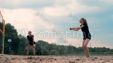 参加职业沙滩排球比赛的妇女。 一名后卫试图阻止两名女子的射击